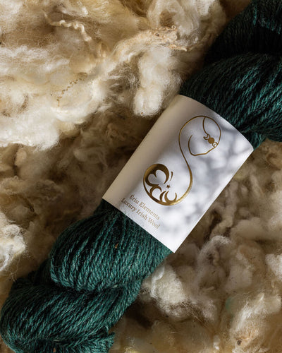 Dark green skein of yarn with Ériu label on a background of raw wool fibers