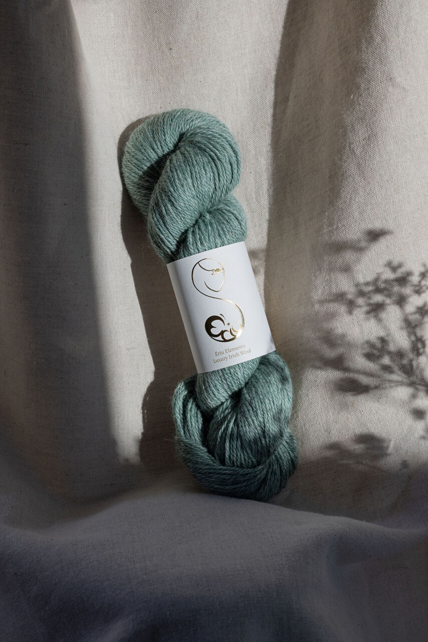 Light muted green skein of yarn with Ériu label on a linen background