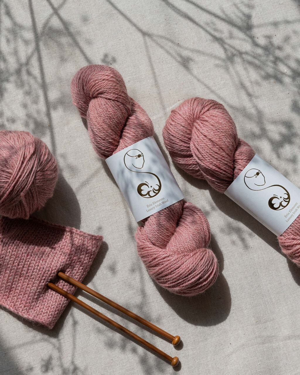 Old rose pink skein of yarn with wooden knitting needles
