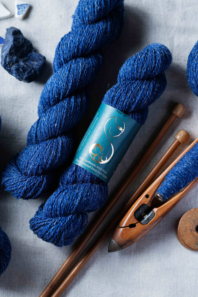 A textured dark blue skein of yarn,
with vintage wooden knitting needles and boat shuttle and blue sodalite stone
