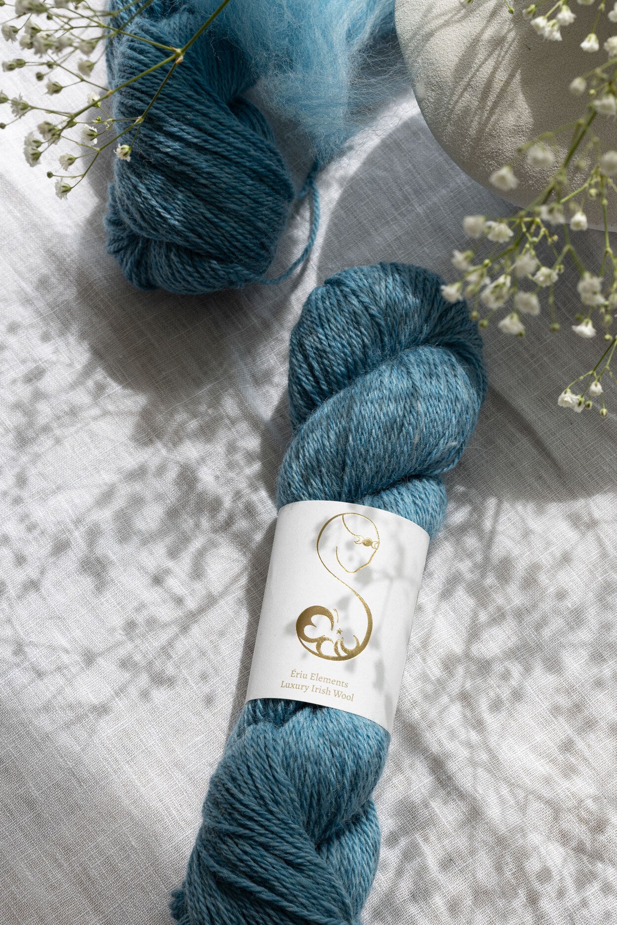 Two soft blue skeins of yarn on a modest floral decorative display